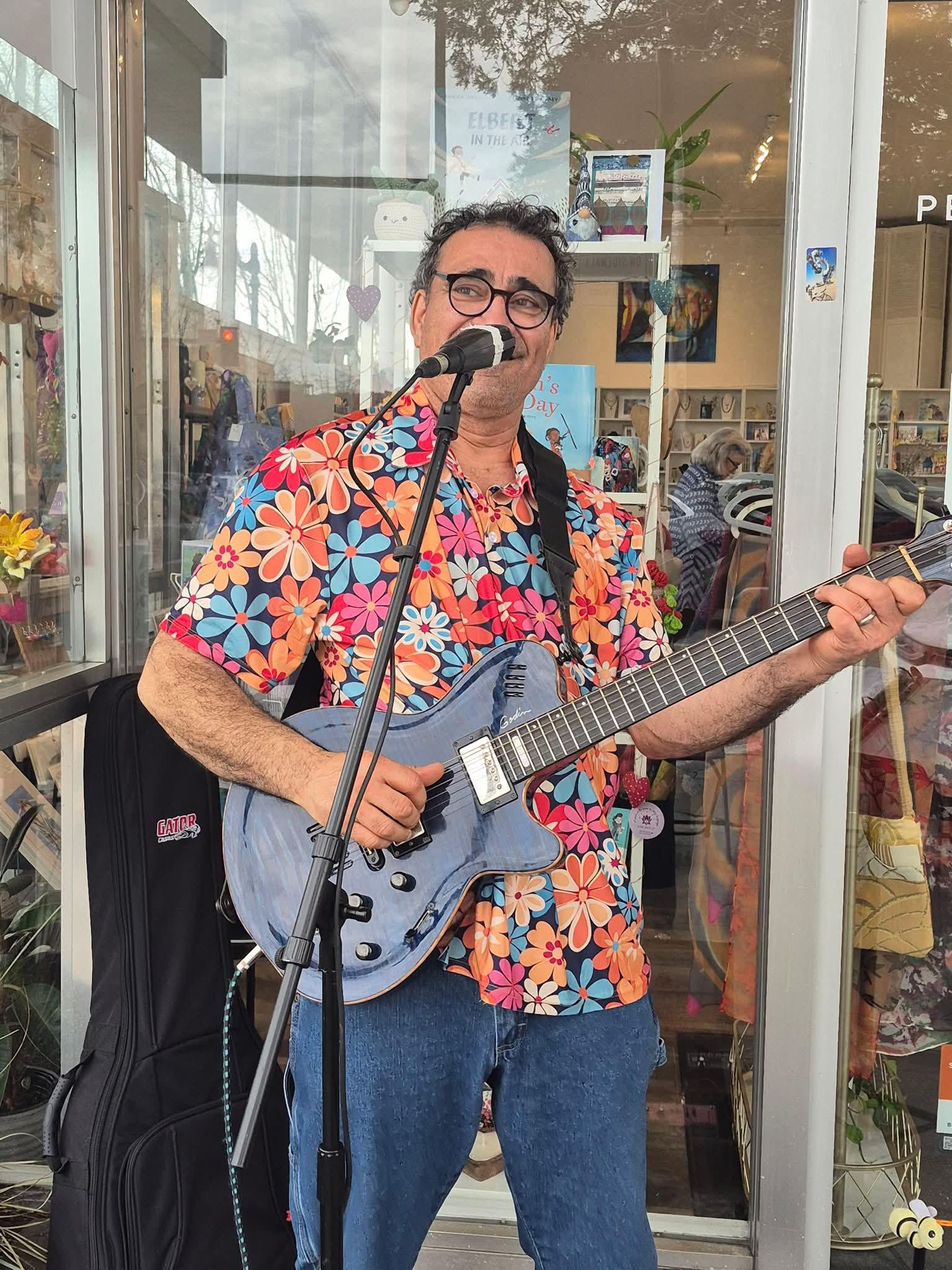 rOjO performing with an electric guitar in a colorful floral shirt